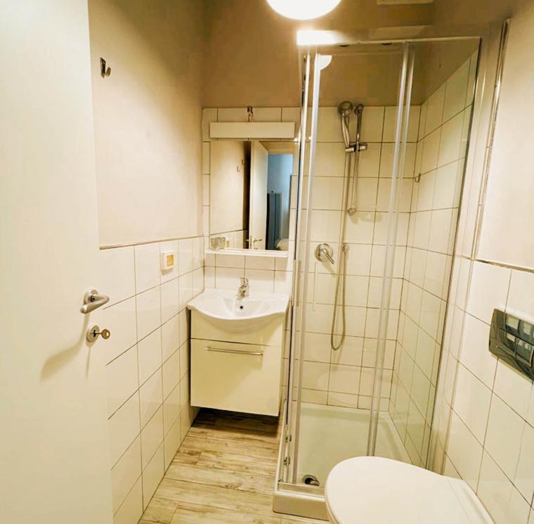 Bagno moderno con doccia, lavabo e WC in uno spazio compatto.