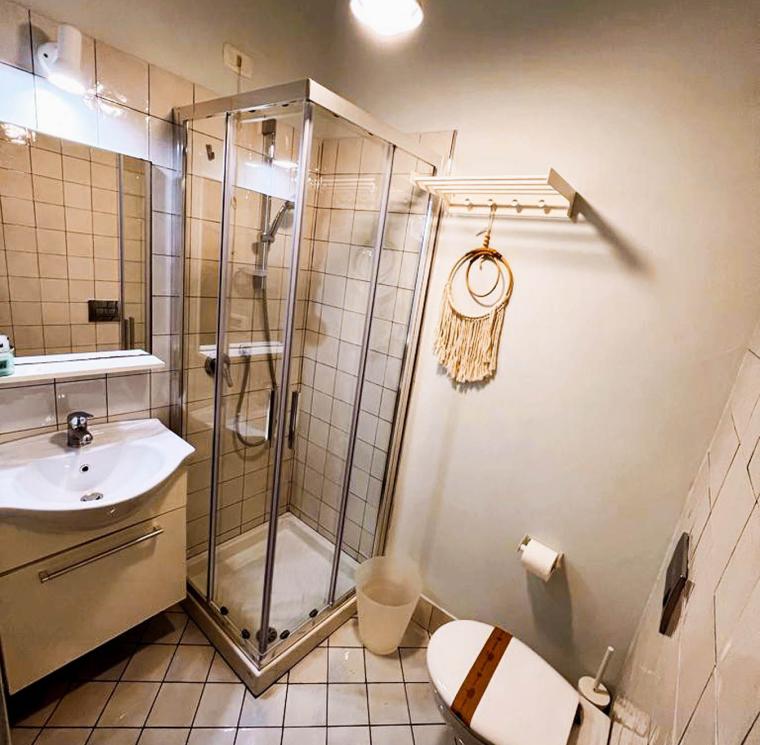 Bagno moderno con doccia, lavabo e decorazione a parete.